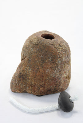 Brown-orange smooth textured granite tiki lamp with small round dark grey stone holding a 9 inch wick.   The wick stone has been removed from the main stone to show the drilled hole which will hold the lamp oil.