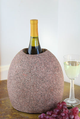 Oval Pink Granite Stone Wine Chiller 9" tall with one  large vertical hole, showing one bottle of wine, set atop small table with red grapes and a glass of white wine.