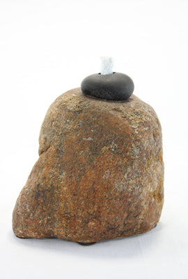 Brown-orange smooth textured granite tiki lamp with small round dark grey stone at the top holding the wick.  Wick is protruding vertically from the top stone about 1 inch.
