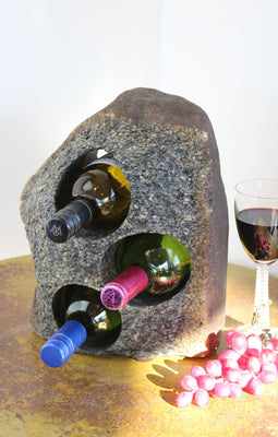 Grey-Brown Granite Stone Wine Rack holding 3 bottles of wine horizontally,  set atop a small table with red grapes and a glass of red wine.
