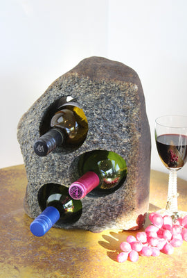 Grey-Brown Granite Stone Wine Rack holding 3 bottles of wine horizontally,  set atop a small table with red grapes and a glass of red wine.